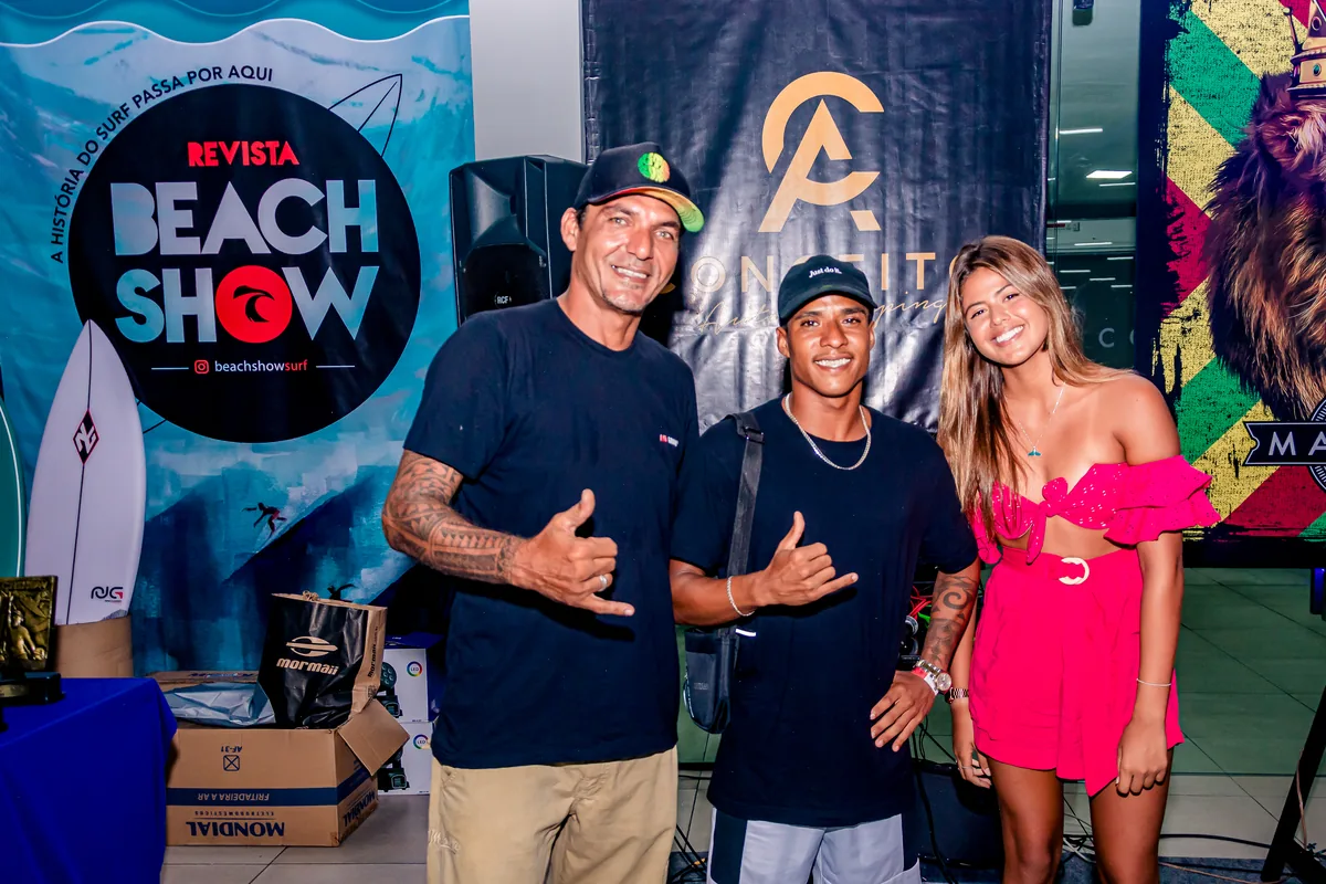 Trio posando em frente ao painel Beach Show
